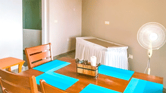 Dining area with a long wooden table, colourful place-mats, and modern decor in a well-lit room at Ibex Resorts, Coonoor (Tapas). 