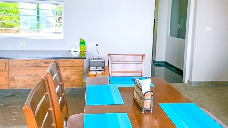 Dining area with long wooden table, colourful place-mats, wooden chairs and modern decor at Ibex Resorts, Coonoor (Tapas).