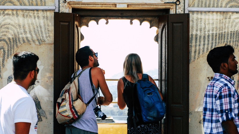 2 foreign tourists peeping outside a window at the City Palace, Udaipur.