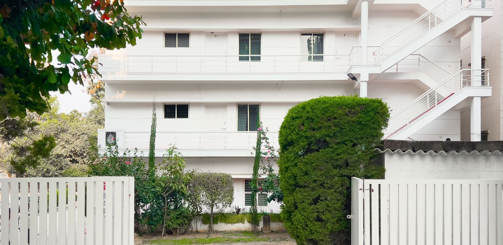 Entrance view of The Pinnacle with white gates and greenery at The Pinnacle, Electronic City.