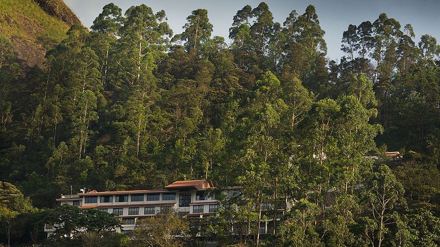 Abad Copper Castle building nestled among lush green trees on a hillside.