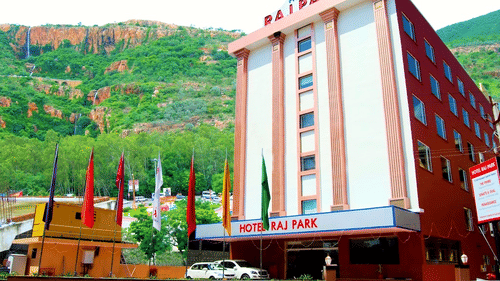 Facade of Raj Park Hotel, Tirupati, with a green mountain in the background.