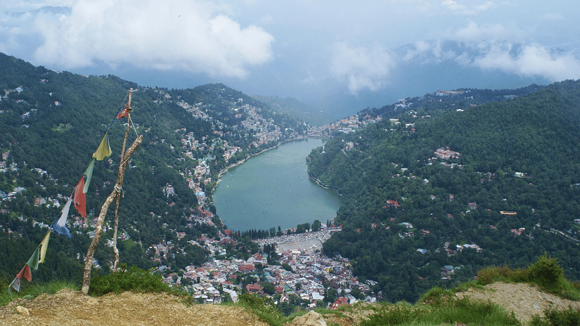 Panoramic view of a town around a lake, with hills and clouds in the background.