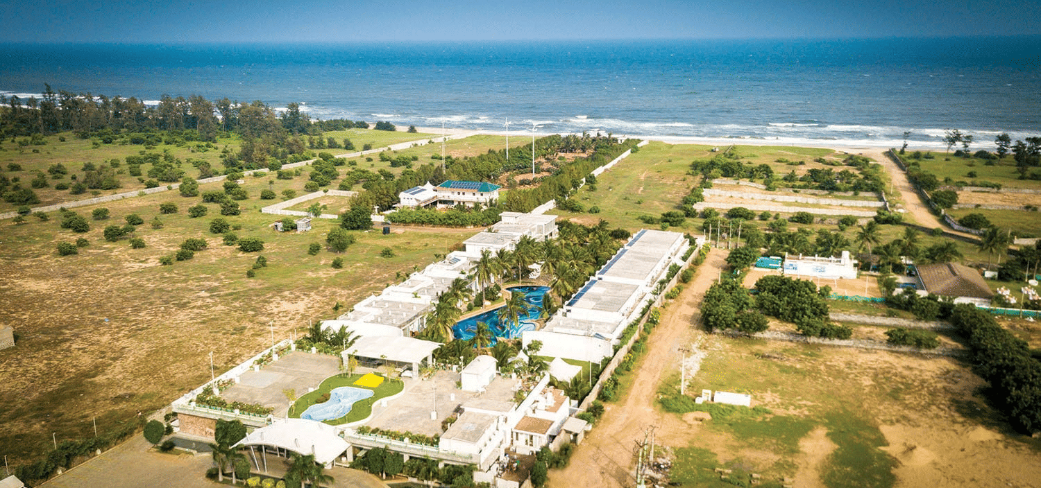 An aerial view of Grande Bay Resort & Spa, one of the best Mamallapuram resorts, featuring the blue sky & ocean stretching towards the horizon.
