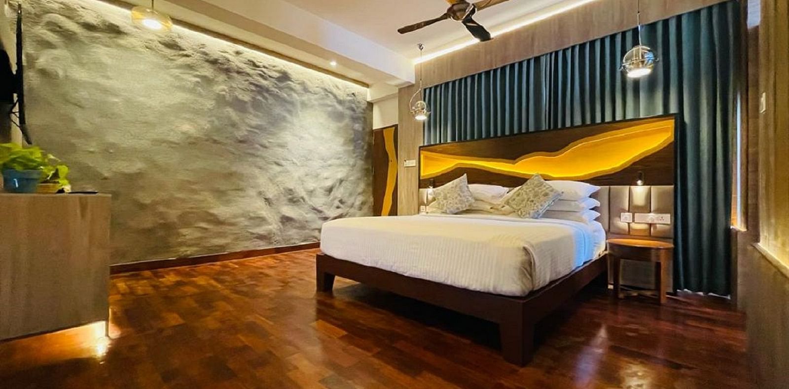 An image of timber Lodge room with a king size bed, ceiling fan, decorative items, and wall paintings - GReaT trails Kodaikanal by GRT Hotels