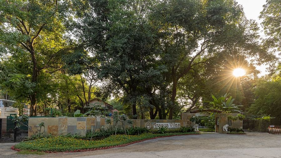 exterior image of aranya vilas featuring the resort logo on the wall on a bright morning with a bright sun in the background