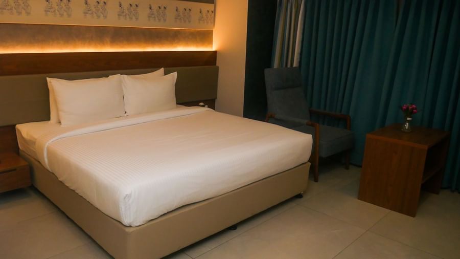 A comfortable hotel bedroom with a neatly made bed and soft lighting, promising a restful stay at Shilton Dee Cee.