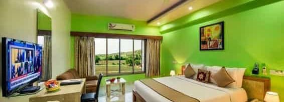 A brightly coloured room with a double bed, a television, and a balcony - Lion Lords Inn Rajula