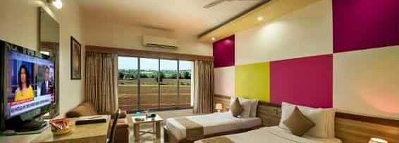 A modern room featuring twin beds with colourful wall panels and a television - Lion Lords Inn Rajula