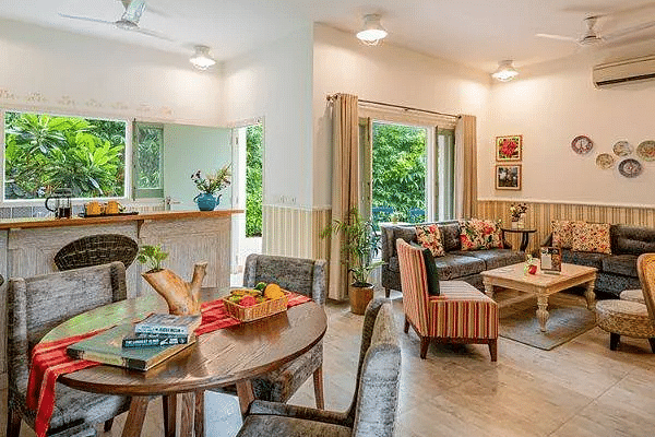 Living and dining area with large windows, chairs, and a table at Karma Chalets.