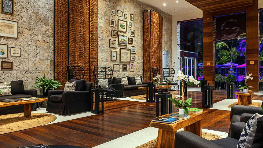 A warmly lit hotel lobby in Jamaica with teapoys and couchec - S Hotel Montego Bay, Jamaica