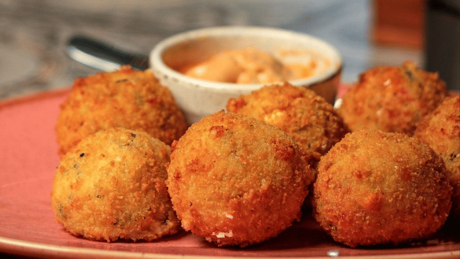A plate of round fried snacks, served with a small bowl of dipping sauce on a table at Amantra Shilpi Resort, Udaipur.