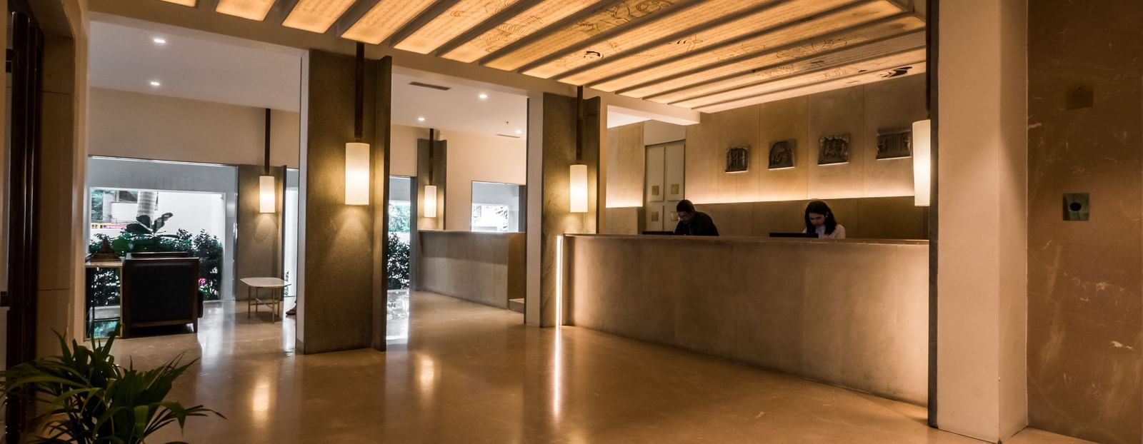 A well-lit hotel lobby or hallway with a wooden slatted ceiling and polished floors, leading to a reception area | Shilton Hotels