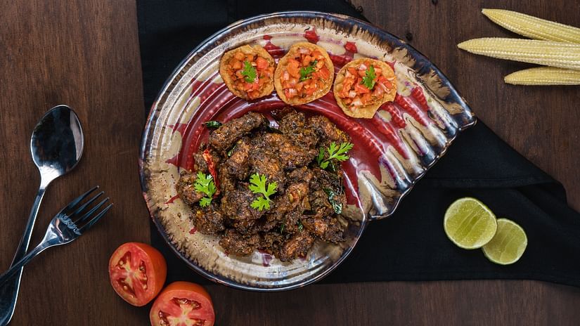 Plated biryani served with sliced vegetables, garnishes, and side condiments on a wooden table.