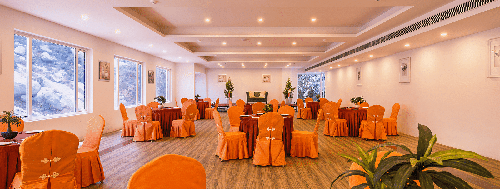 Another view of the spacious dining hall with orange chair covers and round tables set for a meal - TGI Grand Fortuna, Hosur