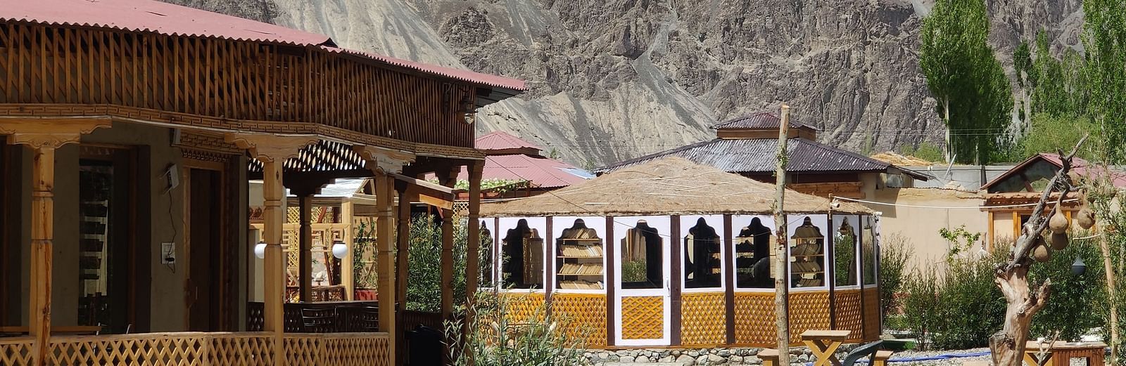 A partial view of the White Sands Resort,Ladakh highlighting the building's design and a swimming pool area with mountains in the distance.