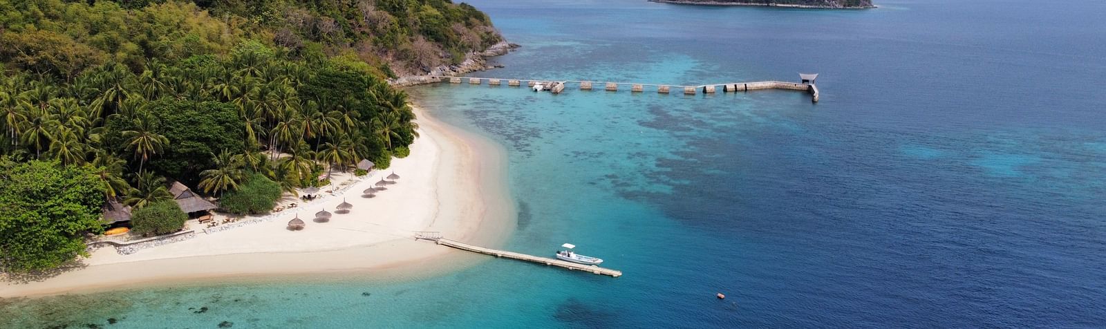 Aerial view of Flower Island Resort surrounded by clear blue water and lush green coastline.