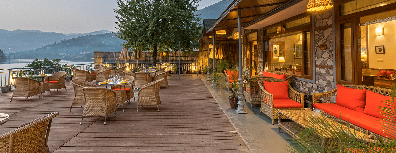 A side angle view of the Outdoor L-Attitude Deck at Fishermen's Lodge, Bhimtal, showcasing its inviting space and scenic surroundings.