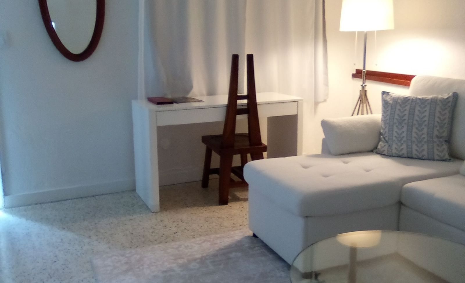 Casa Morada room with a bed, a floor lamp, an oval mirror, and a small glass coffee table.