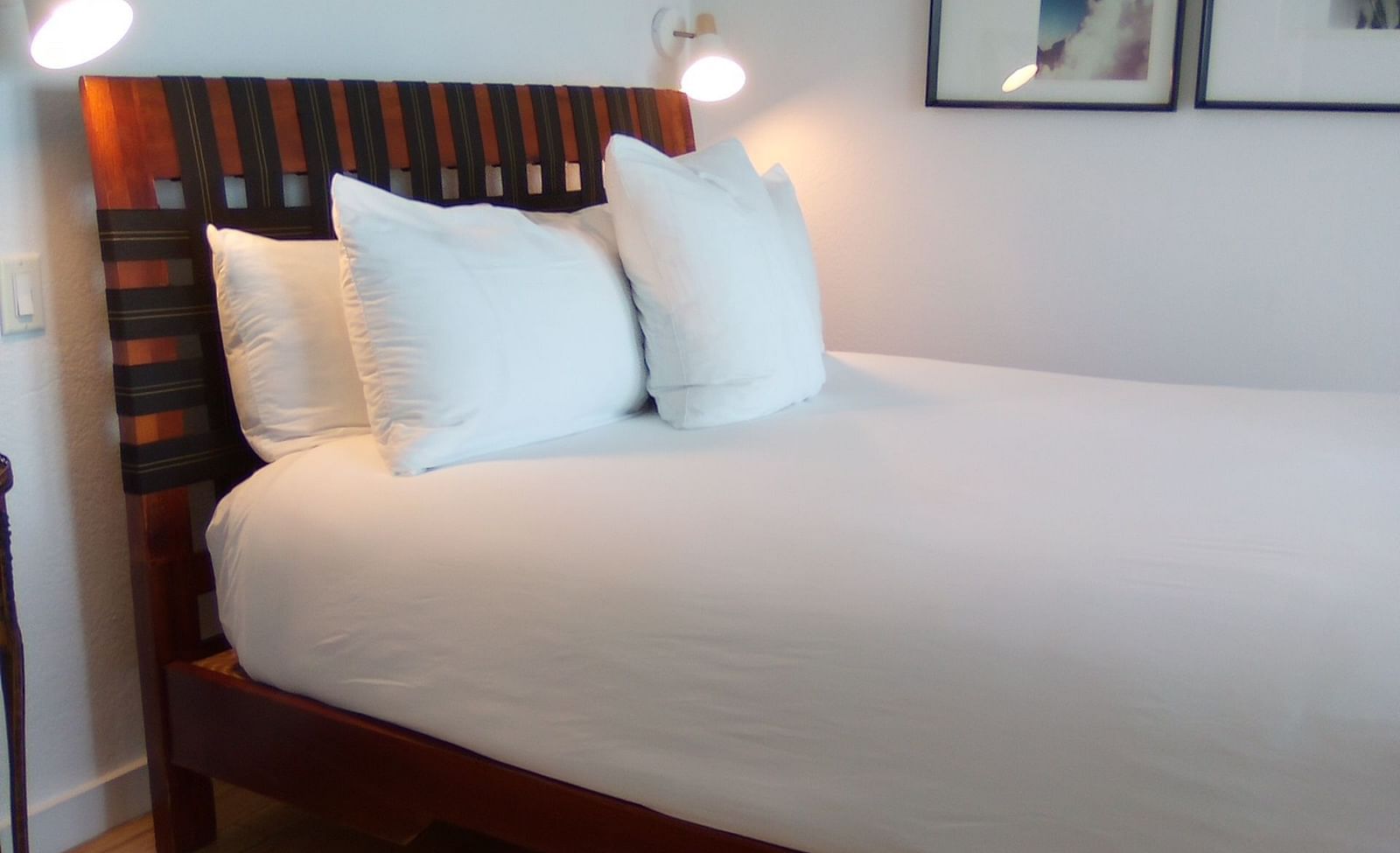 Bed with white linens and wooden headboard at Casa Morada, shown from a side angle.