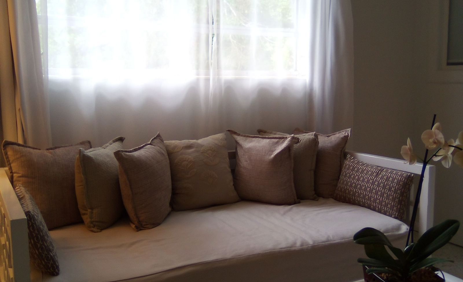 Lounge area at Casa Morada with a beige sectional sofa and a glass coffee table under a sheer curtained window.