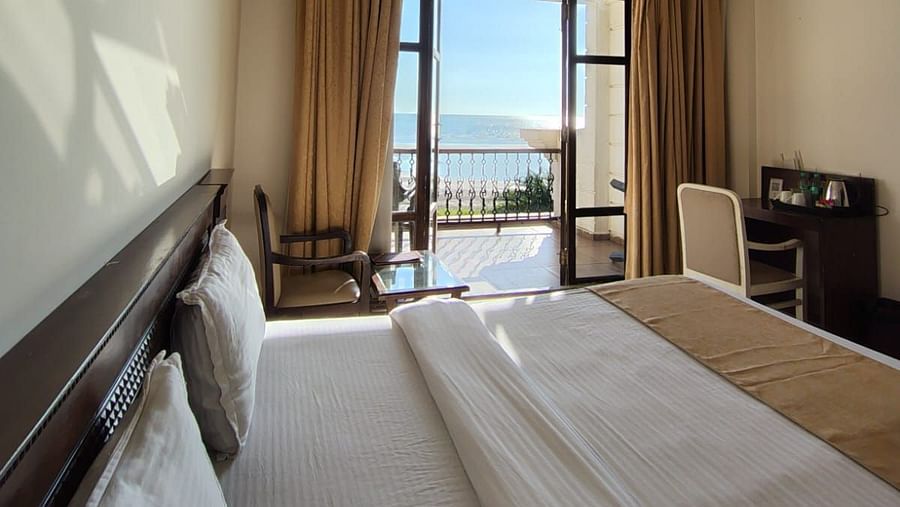 A spacious room at VITS ExcellenSea, Dapoli, with a king-sized bed, a seating area, and a balcony overlooking the ocean.