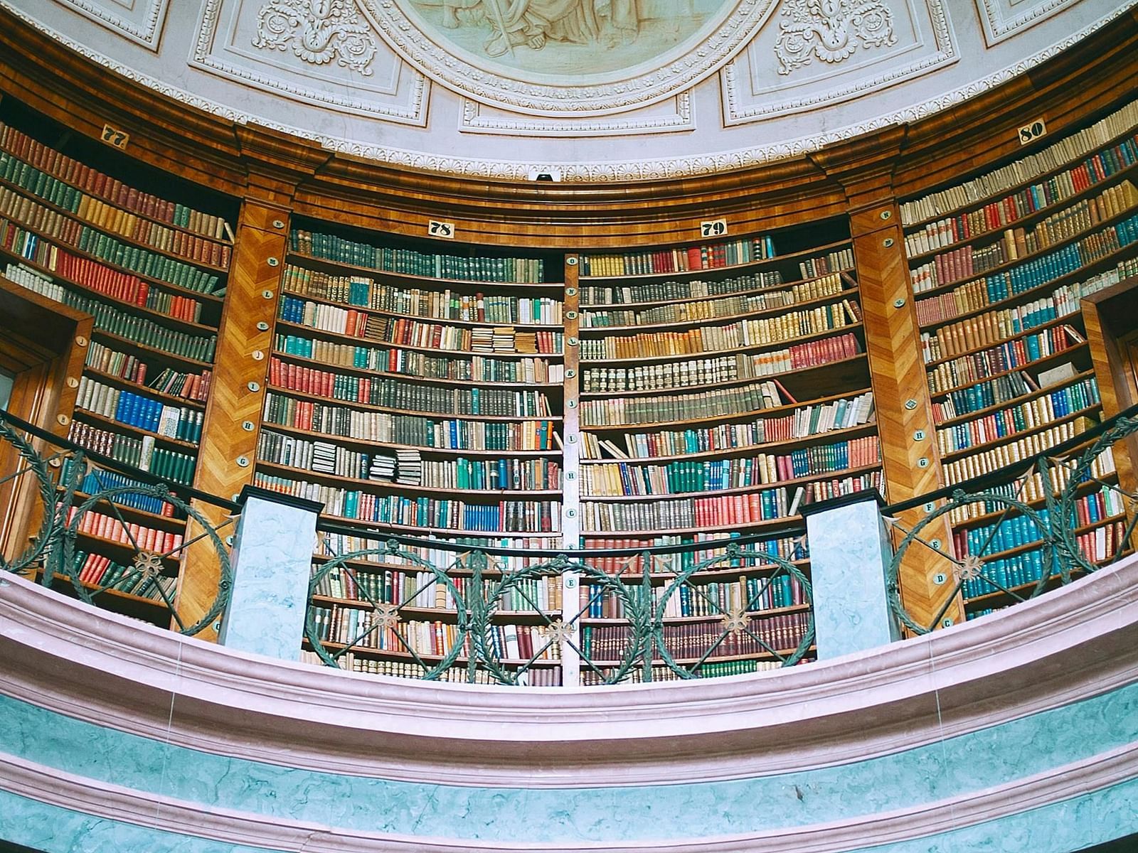 An old library with a dome like ceiling featuring intricate artwork.