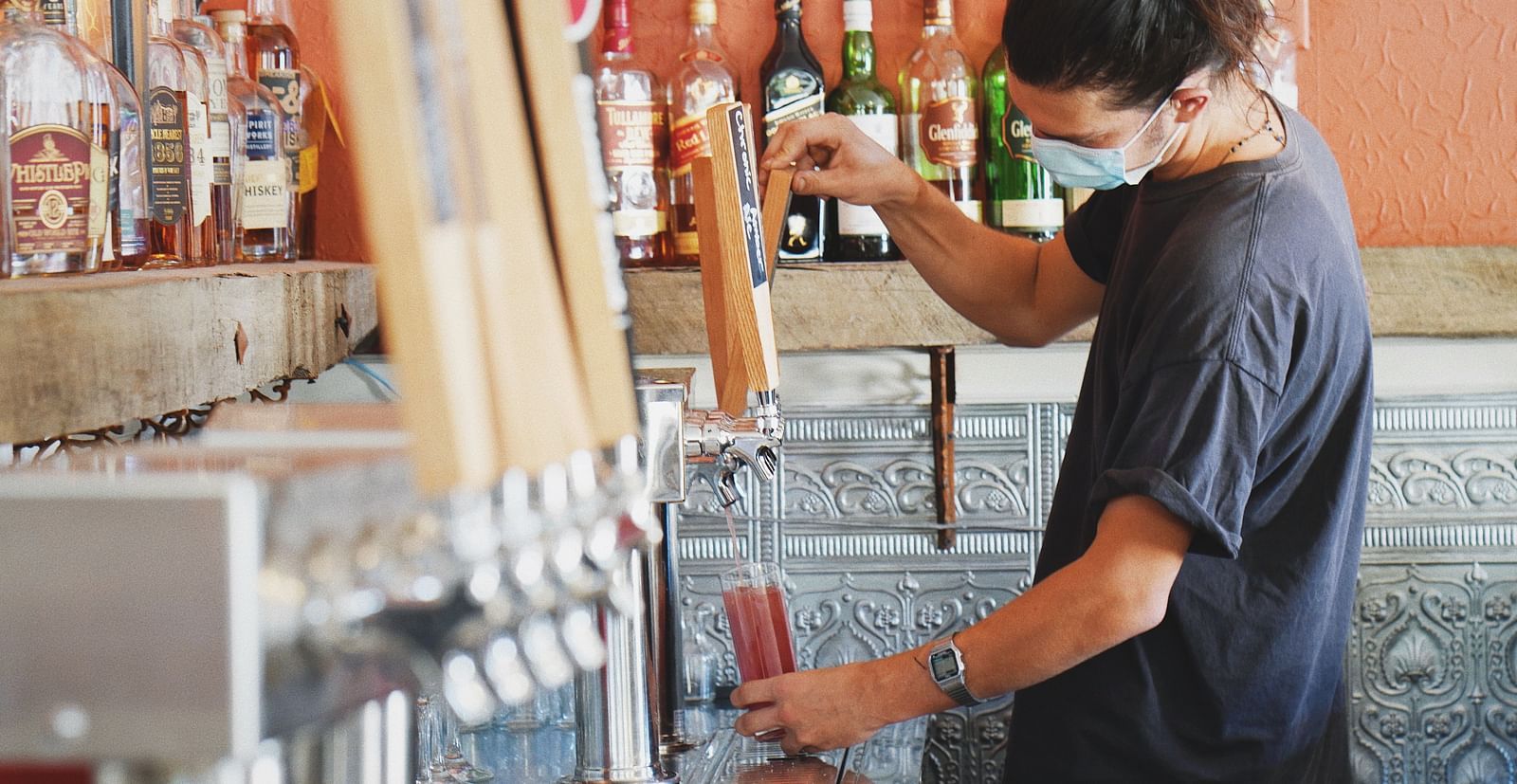 A person pouring beer into a glass in a bar - The Groveland Hotel.
