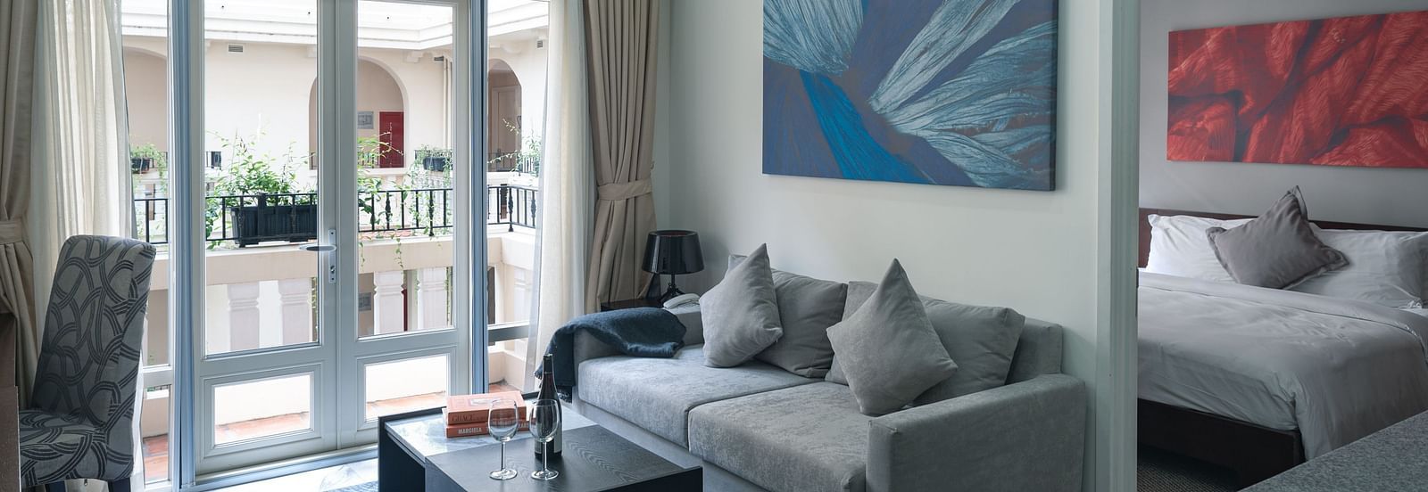 A living room area with a grey sofa, a coffee table, and a painting on the wall | Two-bedroom Suite | Central Mansions, Phnom Penh