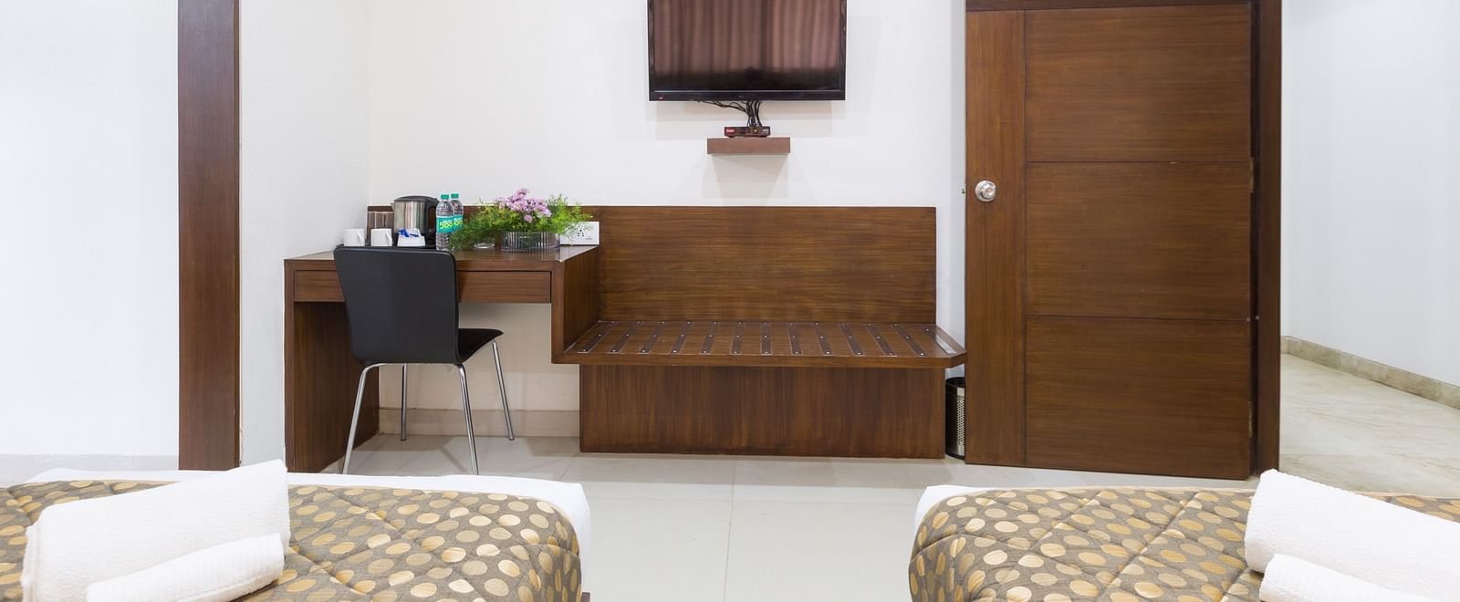 A room with twin beds, a work desk, a television, and a separate seating area - Sanctum Suites BEL Road, Bangalore