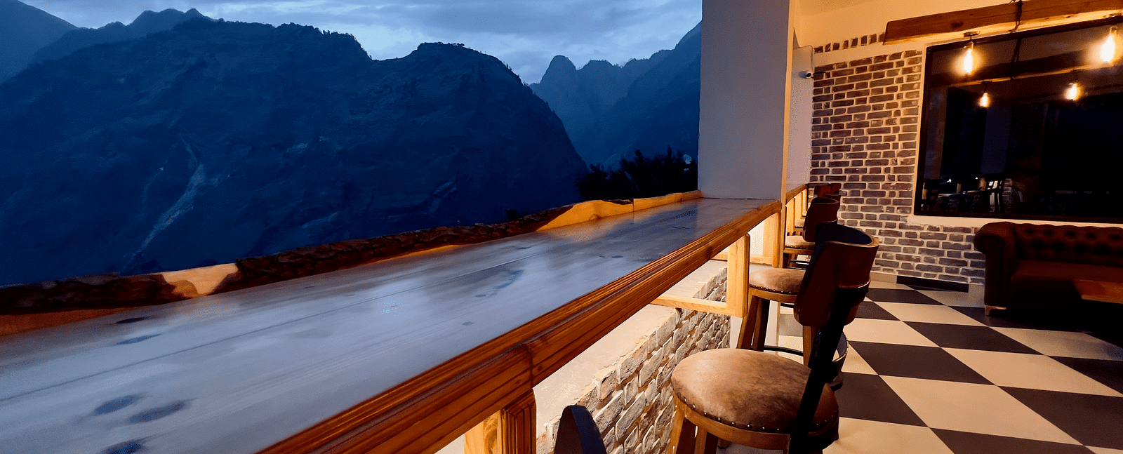 image of the bar with black and white titles and elevated chairs overlooking the beautiful mountain ranges in the background - The Tattva Boutique Resort