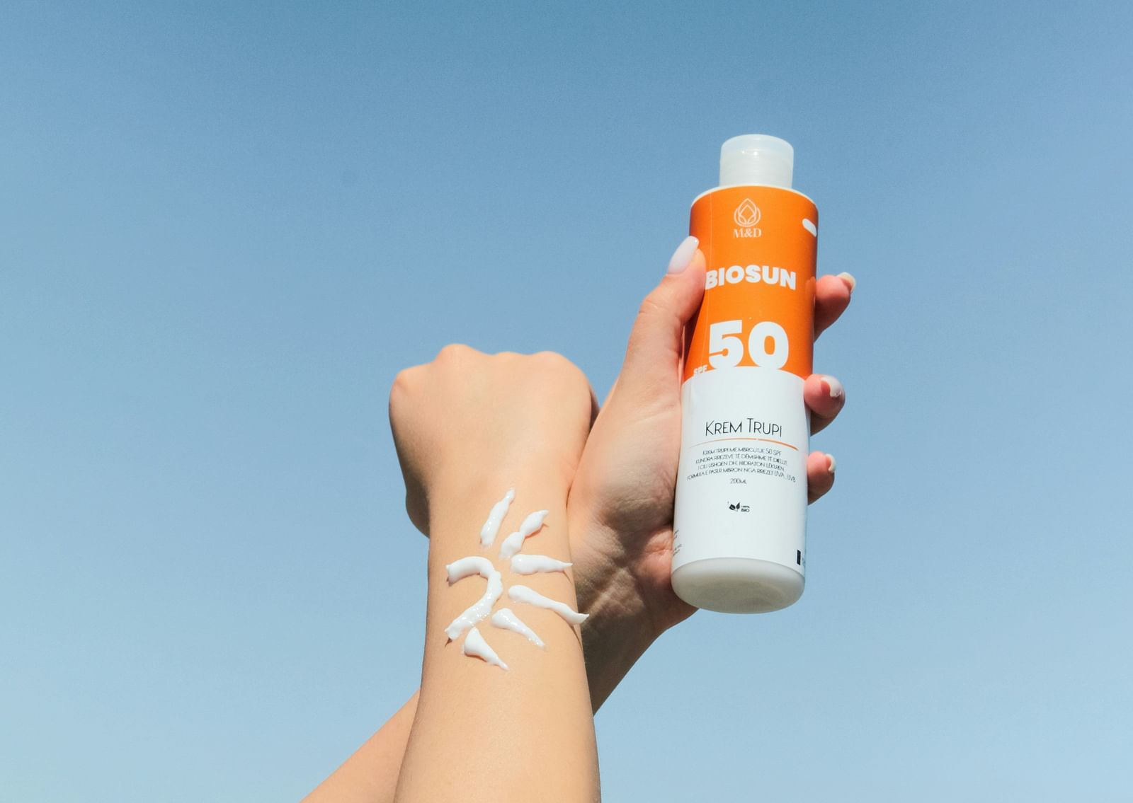 A close up shot of a person with sunscreen on one hand and on the other hand holding a sunscreen bottle.