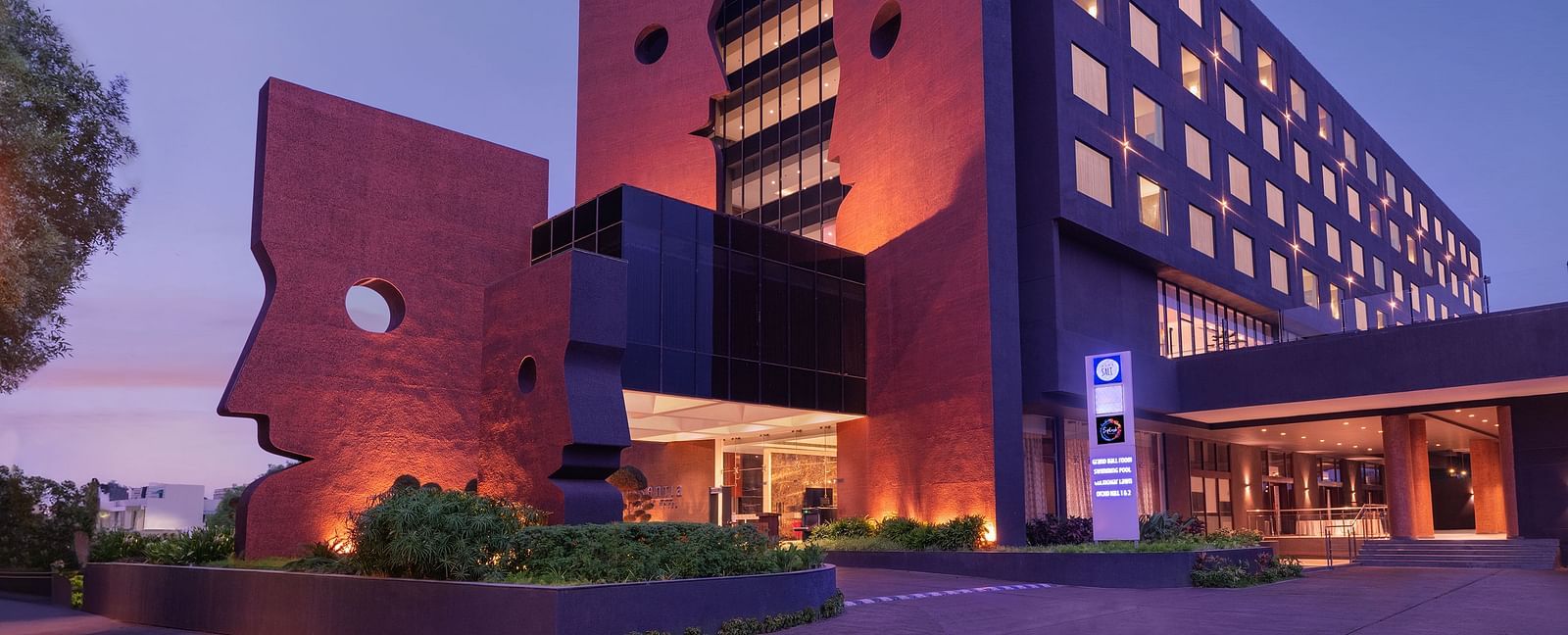 Far out facade view of Essentia Luxury Hotel, Indore during blue hour with the lights on.