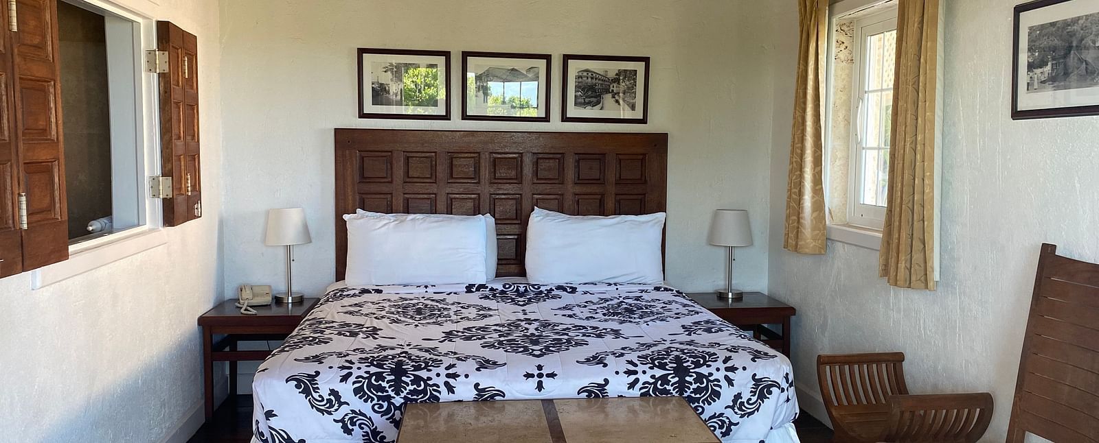 Bedroom with a large bed, ceiling fan, table, chair, and framed art on the wall | A Stone's Throw Away