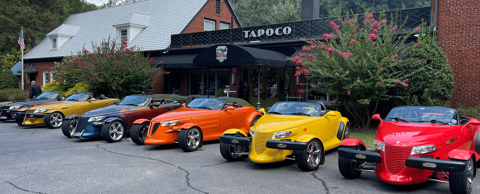 an amazing line up of vintage colorful cars in front of the facade of Historic Tapoco Lodge