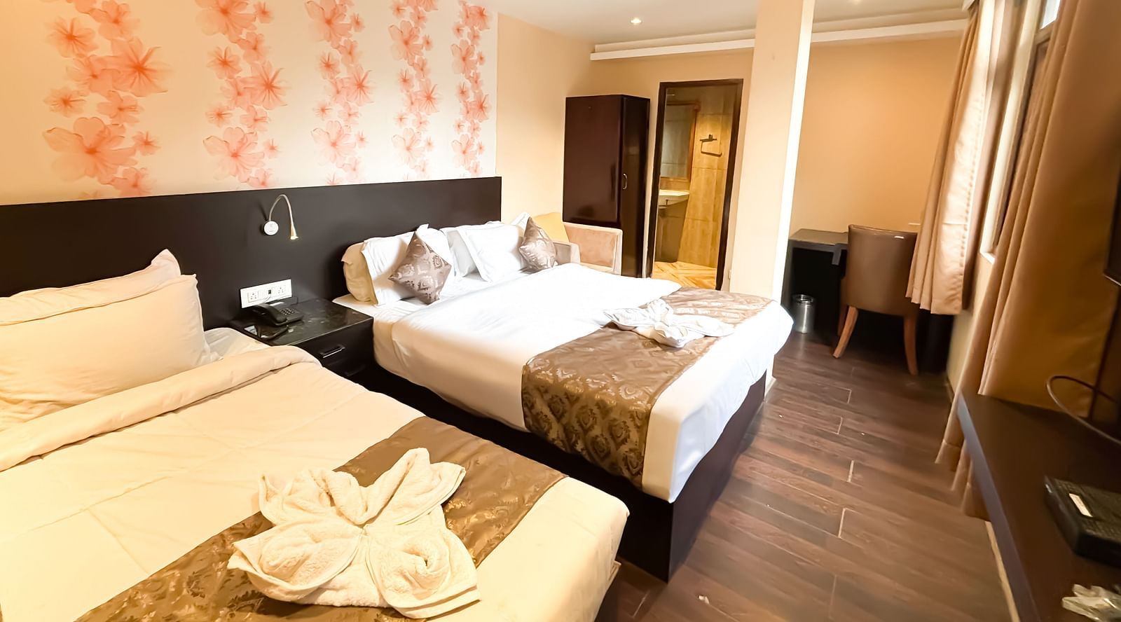 Side view of a twin bed room with flower-printed wallpaper behind the bed, at Avianna Hungry Jack, Gangtok.