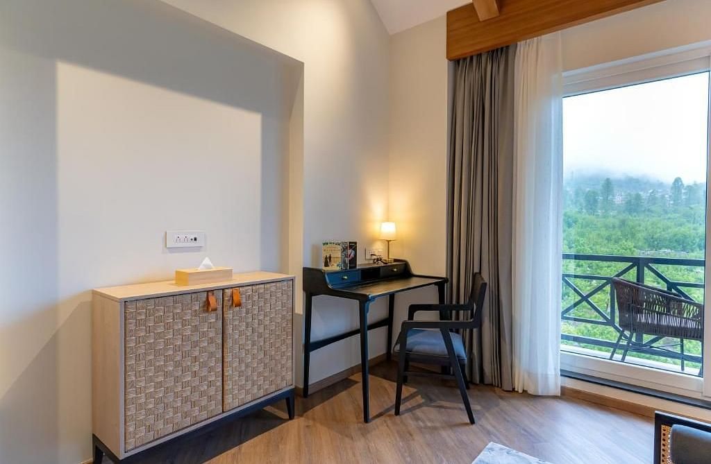 Bright room with a cabinet, desk, chair, and a balcony view at Nivasana Manali.