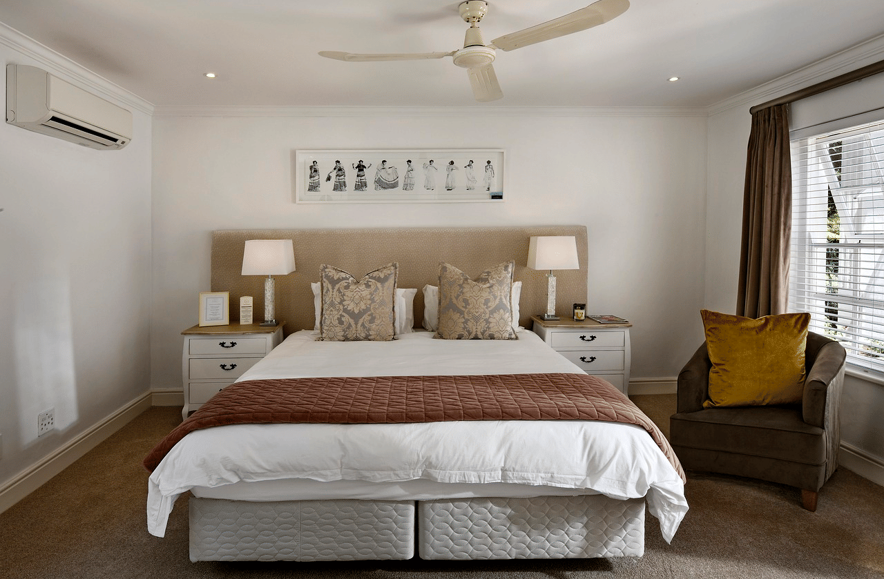 A double bed with a ceiling fan hanging over it in a bedroom.