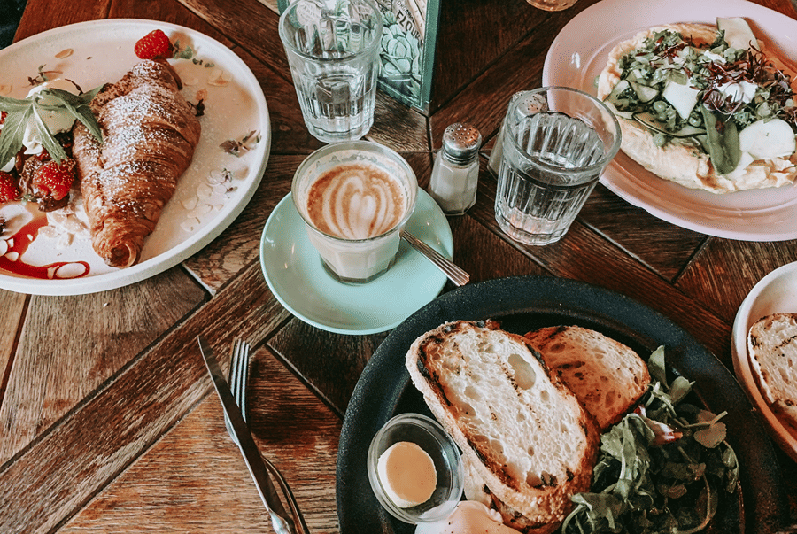 Breakfast table with a croissant, cappuccino, toast and salad.