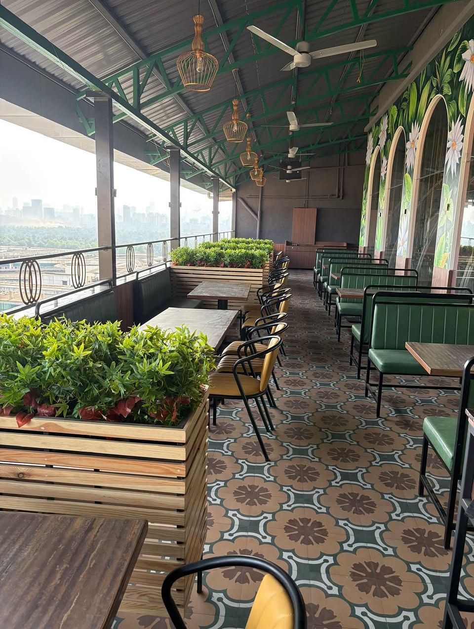An outdoor seating area with tables and chairs is visible, featuring plants and a view of the surroundings - Melior Inn