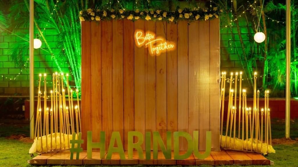 Rustic wooden photo backdrop with the couple's initials and name ‘Harindu’ in glowing lights at Ilara Hotels & Spa, OMR, Chennai