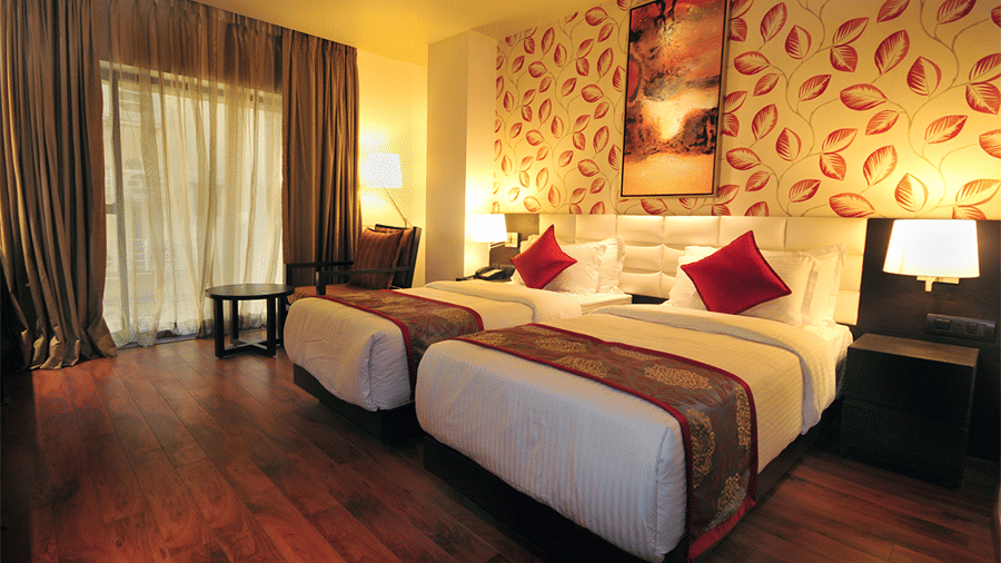 Corner view shot of the Executive Room featuring a twin bed with two brightly lit lamps on the side - Senses Hotel