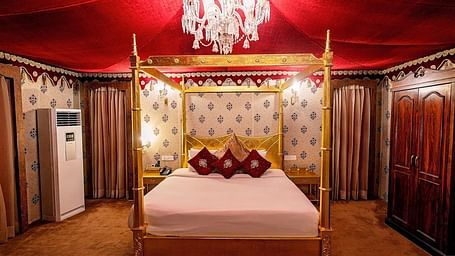 Image of Presidential Suite with a bed and chandelier above the bed at Rajasthali Resort & Spa Jaipur.