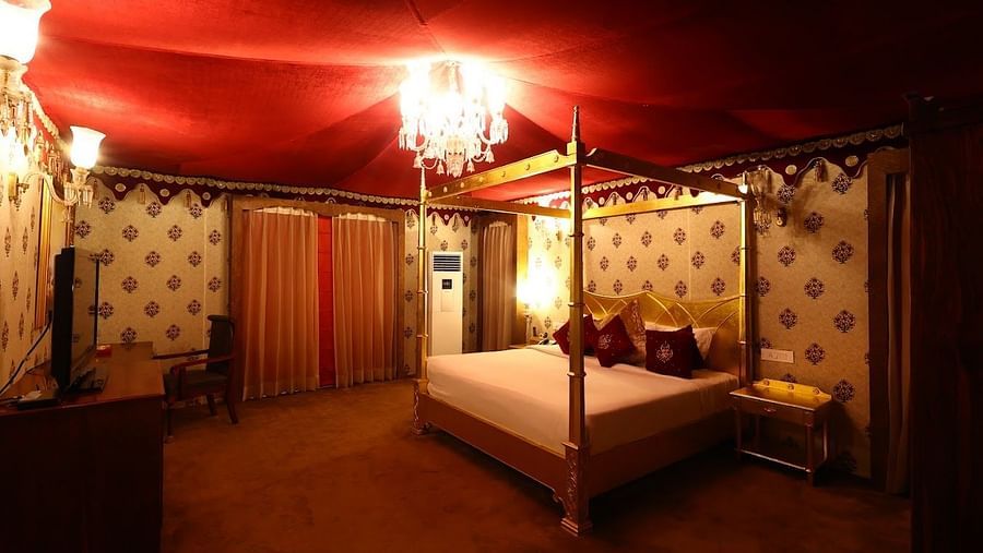 Image of a room with a bed and a chandelier hanging from the ceiling at Rajasthali Resort & Spa Jaipur. 
