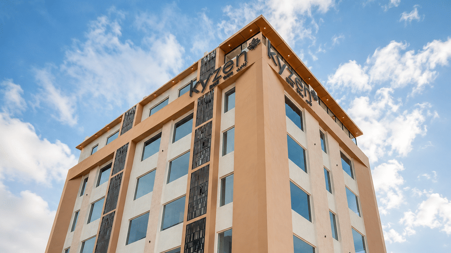 Exterior view of the Hotel Kyzen building against a blue sky at Shamshabad Airport, Hyderabad.