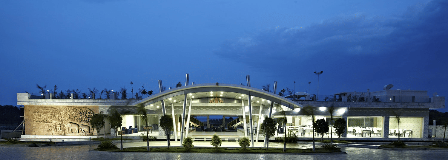 The entrance of Grande Bay Resort & Spa, Mamallapuram, illuminated with bright lights, with the dining area on the right and a view of Arjuna’s Penance on the left.