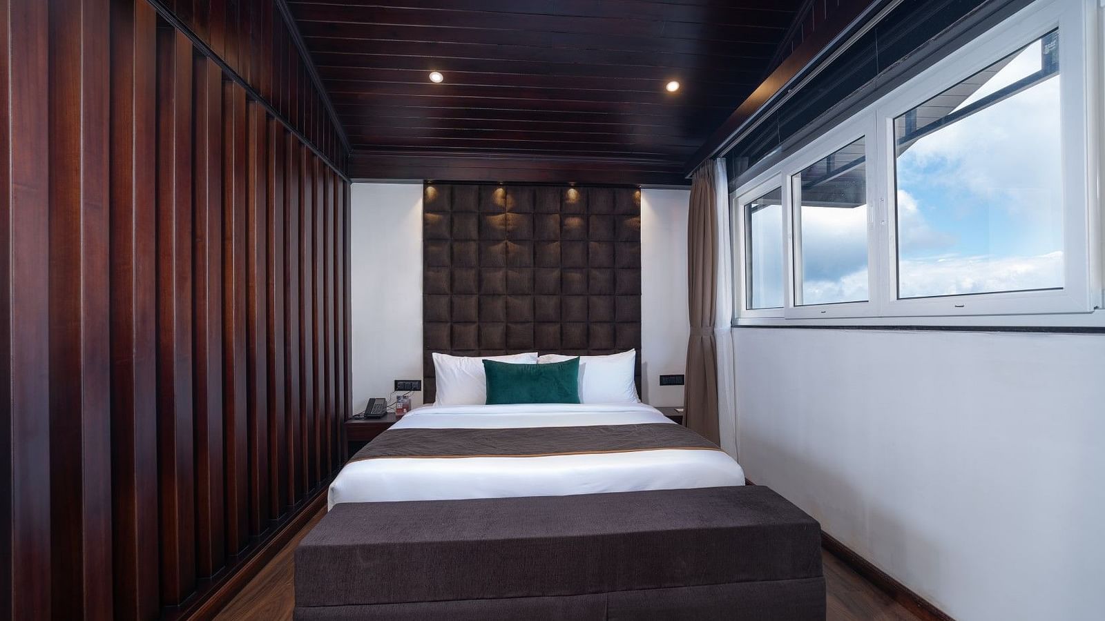 Image of a bed from a different angel featuring a bed, lights and a window.