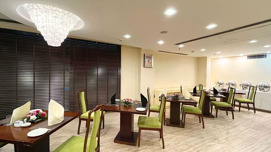 An image of a restaurant featuring several sets of chairs and tables and a chandelier light on top at Five Elements Hotels North Avenue, Delhi