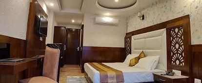 A spacious hotel room with a king size bed, two armchairs, a coffee table, a desk | DLS La Serene Manali