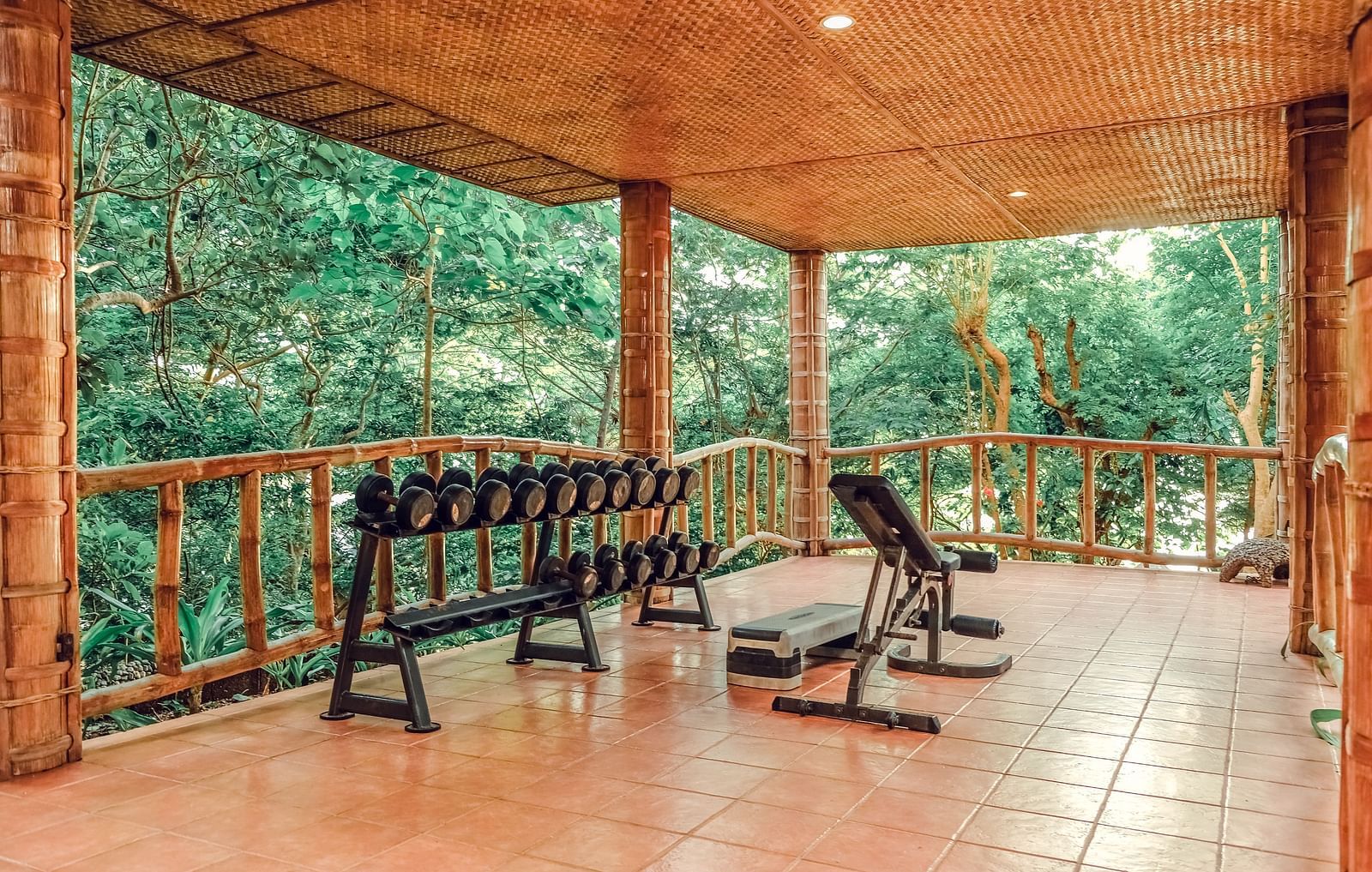 Open-air gym or fitness space with wooden floors surrounded by greenery.